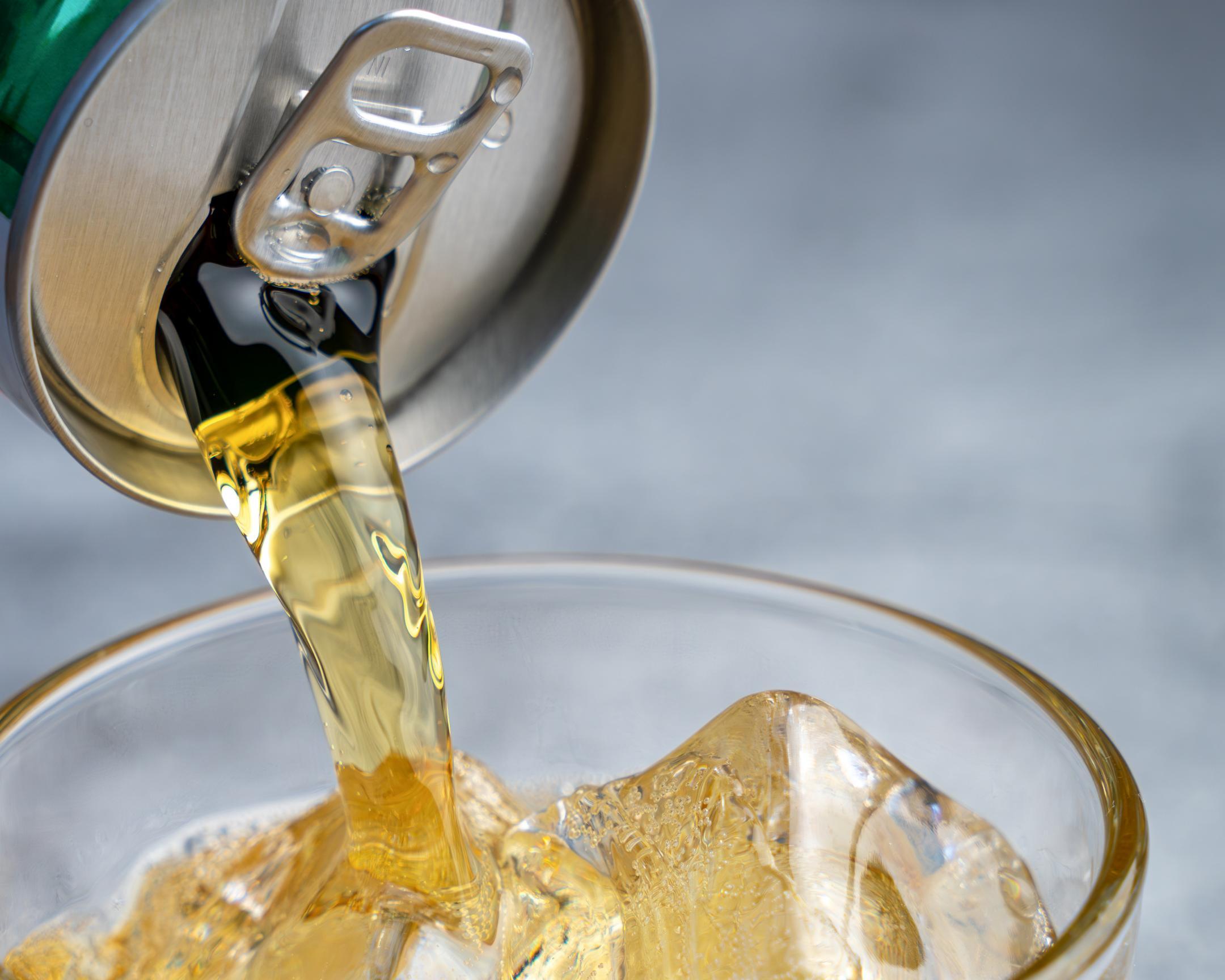 Ein Getränk wird in ein Glas mit Eis geleert.