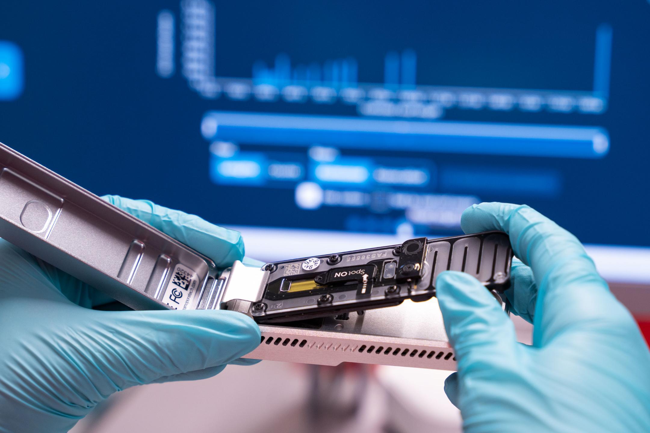 Hände in Handschuhen halten ein modernes Gerät.