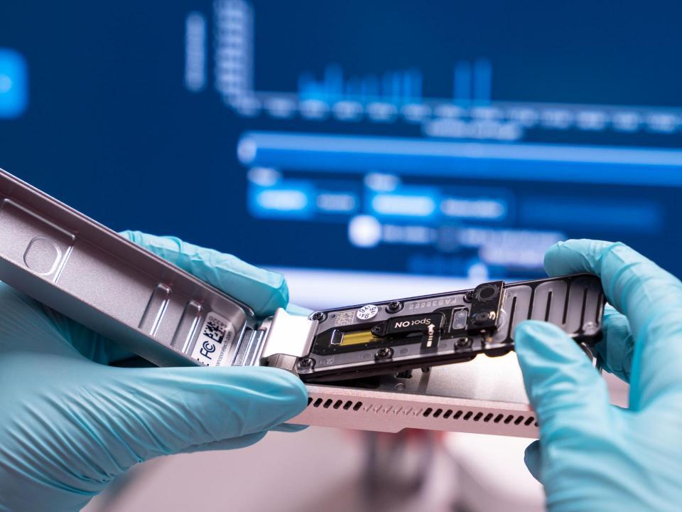 Hände in Handschuhen halten ein modernes Gerät.