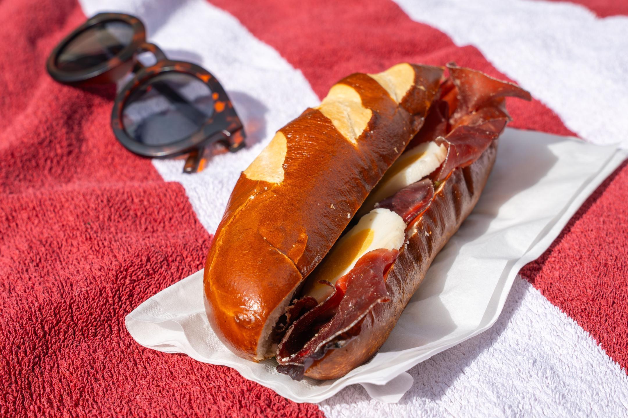 Sandwich und Sonnenbrille liegen auf rotem Badetuch