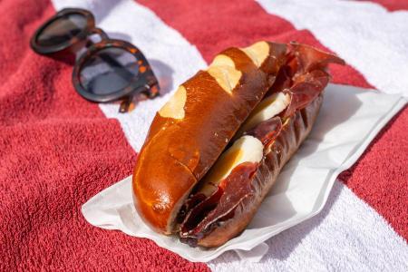 Sandwich und Sonnenbrille liegen auf rotem Badetuch