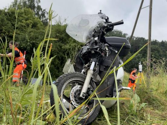 Ein beschädigtes Motorrad; im Hintergrund Polizisten an der Spurensicherung