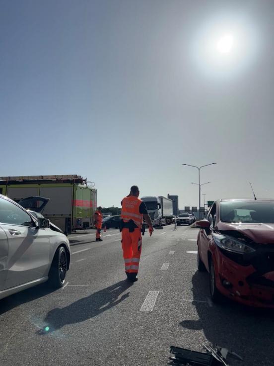 zwei Polizisten bei der Sicherung von Spuren zwischen zwei Unfallautos . Die Sonne scheint stark.