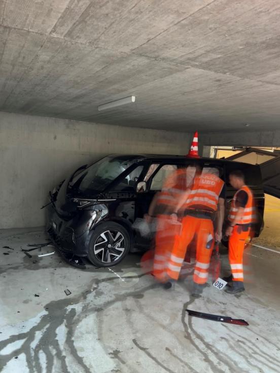 Zwei Polizisten in oranger Schutzausrützung stehen vor einem Unfallfahrzeug