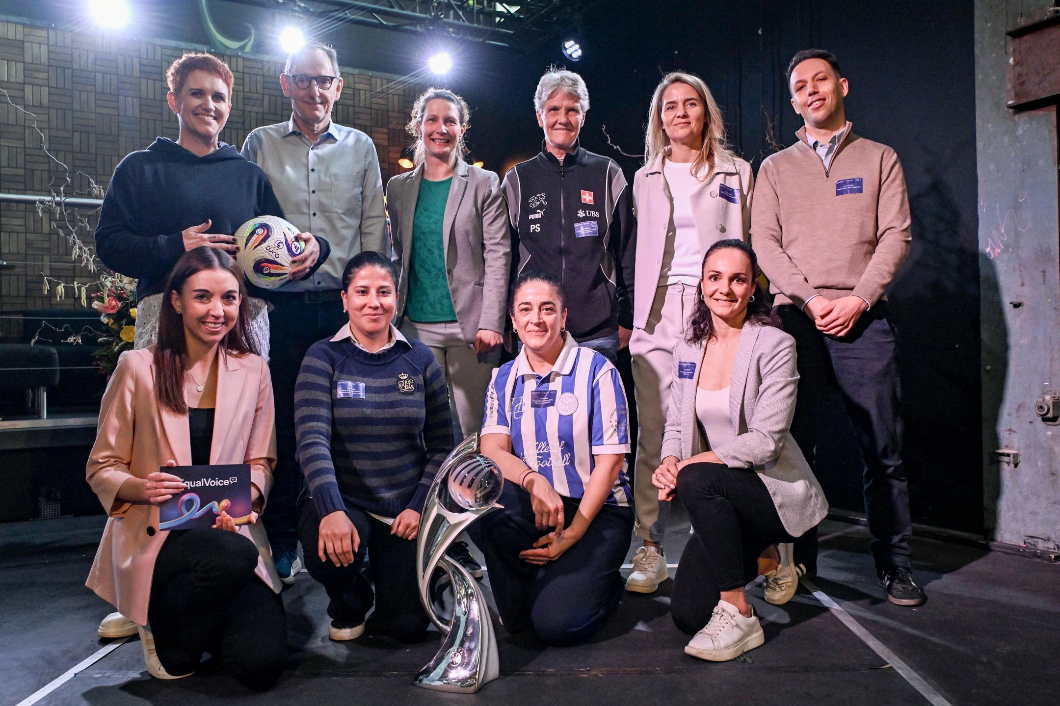 Eine Gruppe von zehn Personen posiert zusammen mit der Schweizer Nationaltrainern Pia Sundhage auf einer Bühne. 