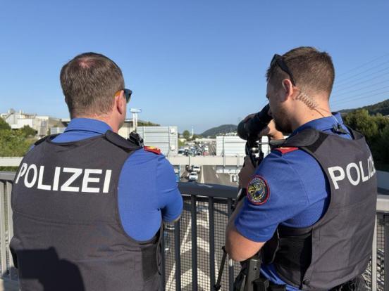 Zwei Polizisten schauen von einer Brücke auf die Autobahn