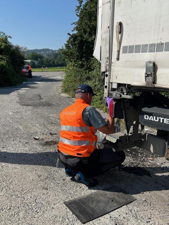 Forensiker sichert knieend neben einem Lastwagen Spuren 