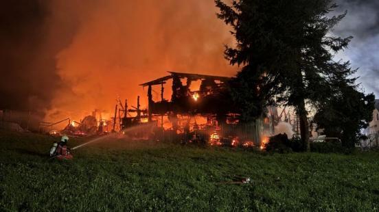 Ein Feuerwehrmann spritzt Wasser in ein brennendes Gebäude