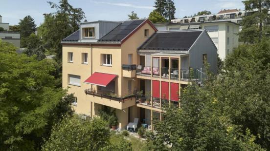 Mehrfamilienhaus mit einer Erweiterung in Form eines Anbaus.