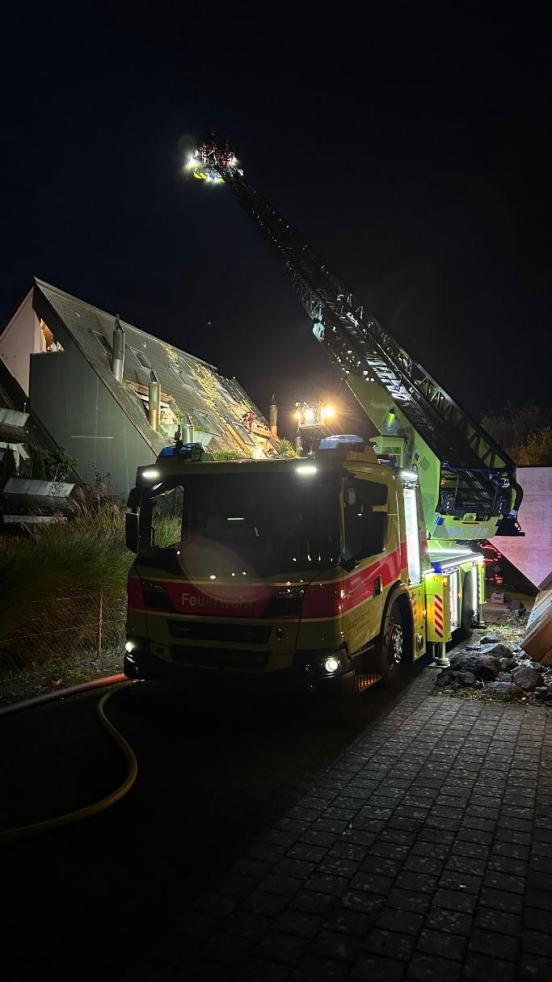 Autodrehleiter der Feuerwehr vor einem Haus bei Nacht