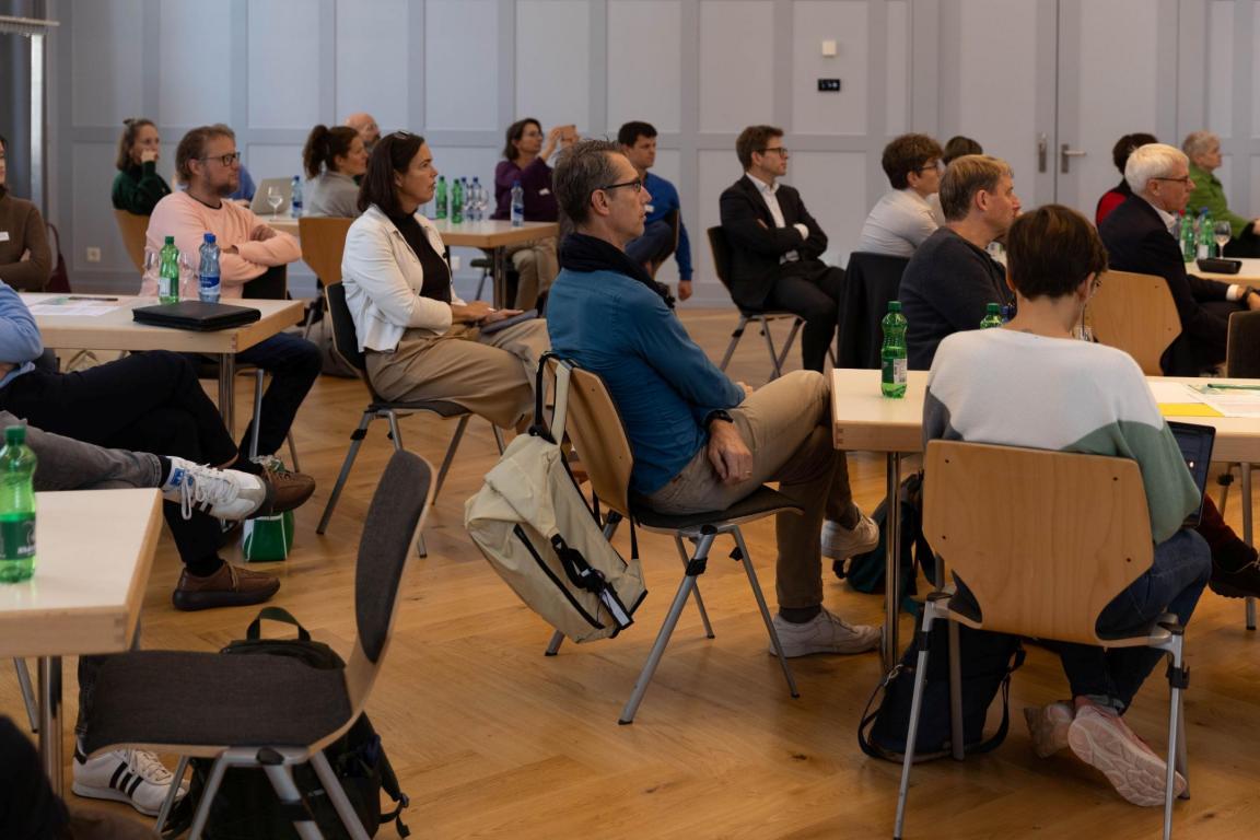 Im Saal sieht man die verschiedenen Besucherinnen und Besucher an den Tischen sitzen.