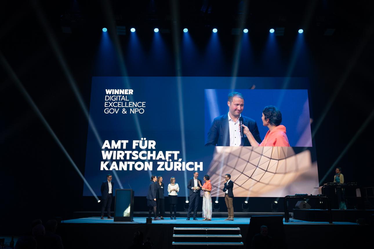 Sandbox-Projektleiter Raphael von Thiessen wird auf dem Podium interviewt. Weitere Personen stehen auf der Bühne, im Hintergrund ist das Logo des Amts für Wirtschaft und das Wort «Gewinner» zu sehen