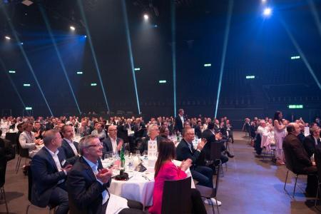 Viele Menschen sitzen um verschiedene Tische und applaudieren