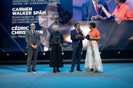 Cédric Christmann, CEO von Primeo Energie, die Zürcher Regierungsrätin Carmen Walker Späh und Bundesrat Albert Rösti stehen auf der Bühne. Rösti wird von einer Moderatorin interviewt.
