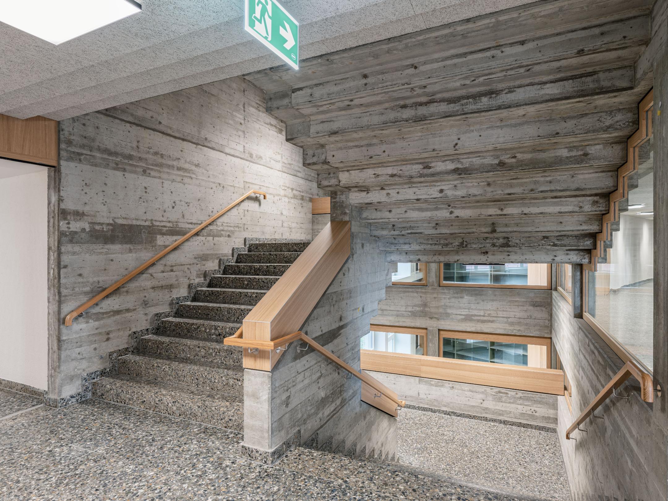 Markantes Treppenhaus aus Beton mit Holzelementen. 