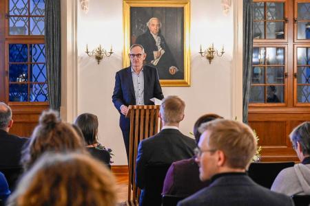Ein Mann in Anzug spricht an einem Pult aus Holz, im Hintergrund ist ein Bildschirm mit Sportpreis Kanton Zürich zu sehen.