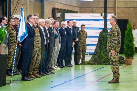 Der Kreiskommandant beginnt mit der Entlassungszeremonie. Er steh vor den Ehrengästen.