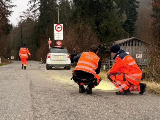 Polizisten knien auf der Strasse und suchen nach Spuren
