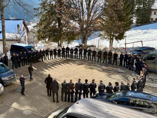 Zahlreiche Polizisten stehen in einem Halbkreis um eine Person