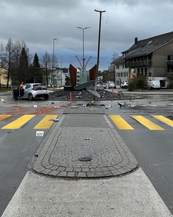 Ein stark beschädigtes Fahrzeug steht in einem Kreisel. Rundherum liegen Trümmerteile