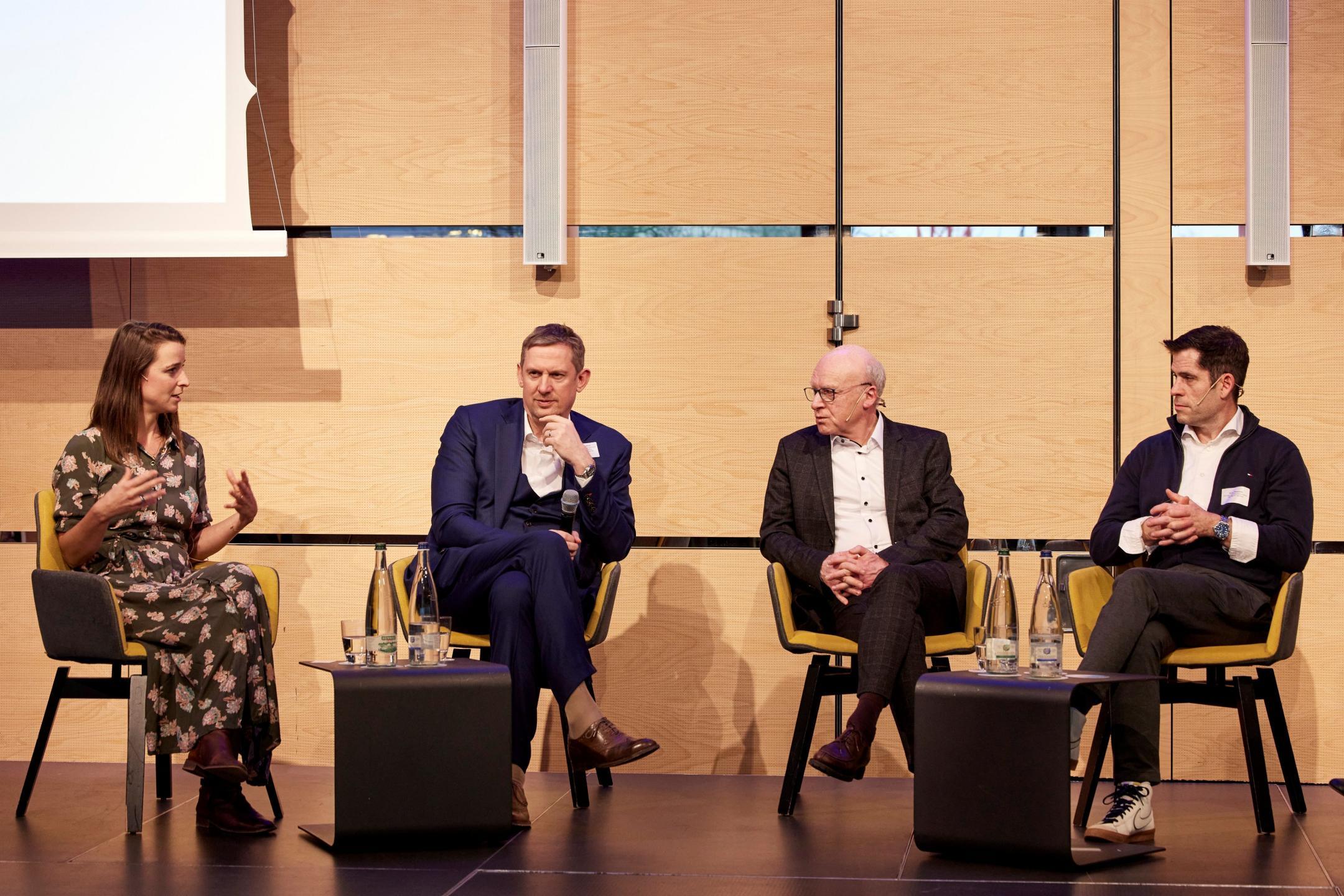 Vier Personen sitzen auf einer Bühne und diskutieren miteinander