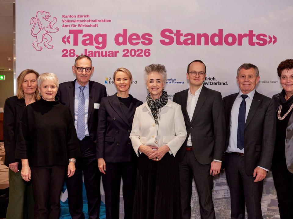 Der gesamte Zürcher Regierungsrat posiert vor einem Plakat mit der Aufschrift «Tag des Standorts 2026»