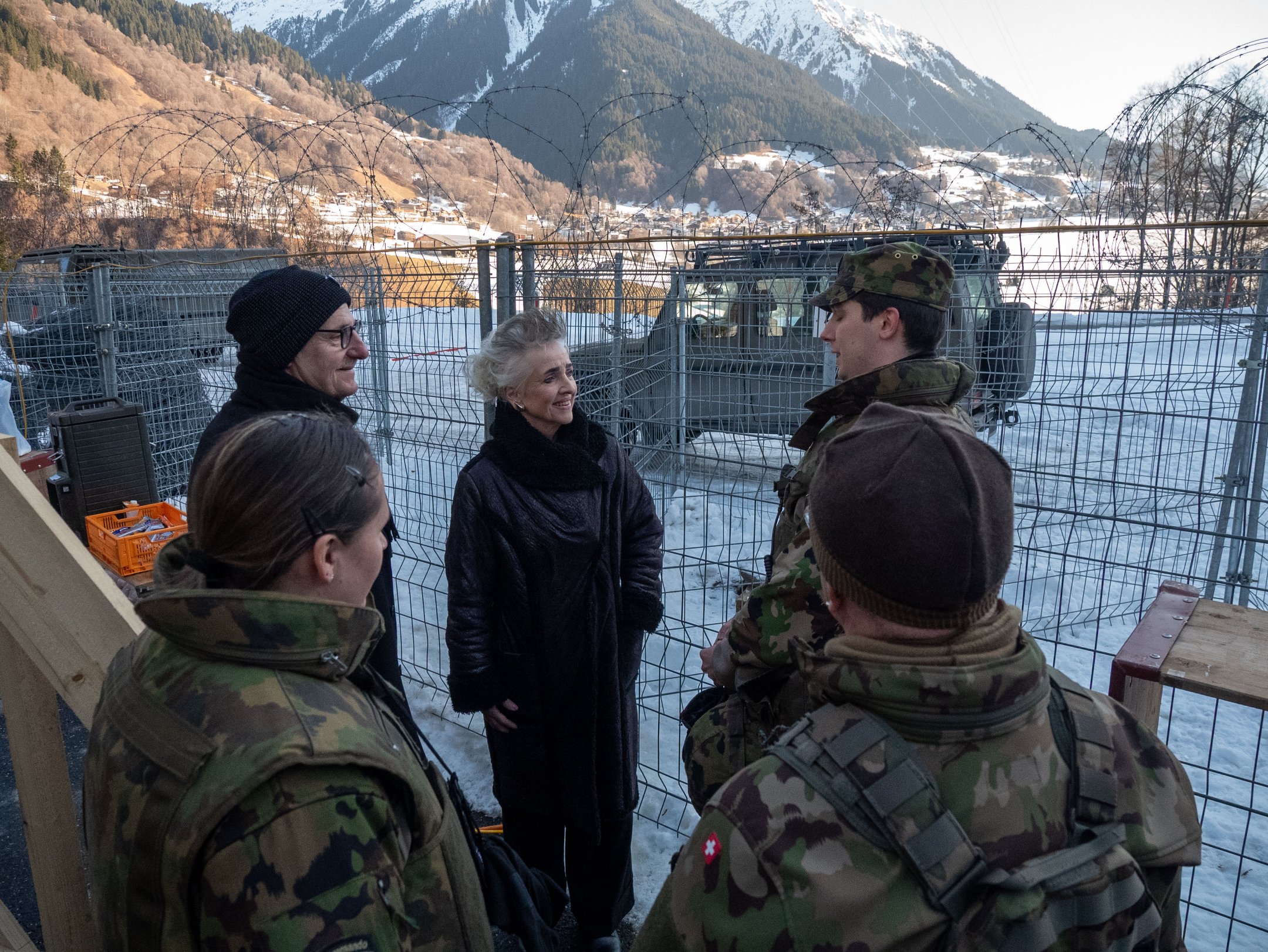 stehen draussen vor einem Schutzgitter und unterhalten sich.