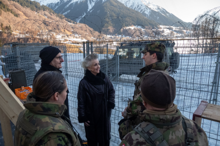 stehen draussen vor einem Schutzgitter und unterhalten sich.