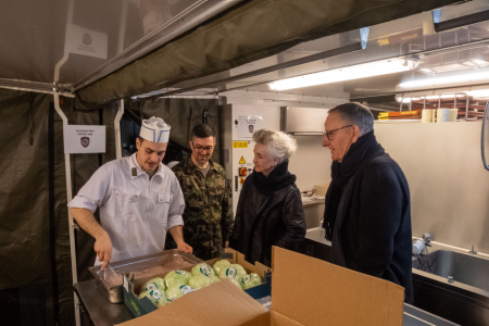 Ein Koch der Schweizer Armee steht in der Küche vor einer Kiste Esswaren.