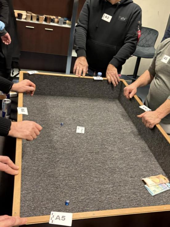 Ein Spieltisch mit Würfeln und Bargeld; Personen halten die Hände auf den Rand