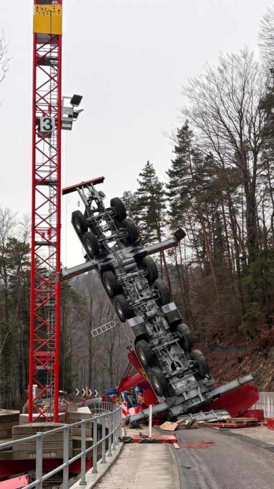 Ein verunfallter Pneukran auf einer Baustelle ragt mit dem Chassis in die Höhe