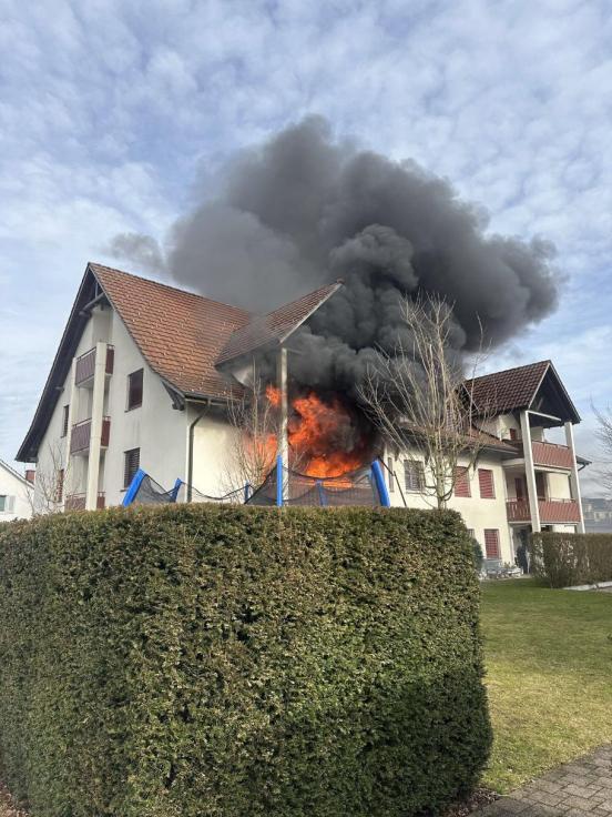 Ein Haus aus dessen Fenster Flammen lodern.