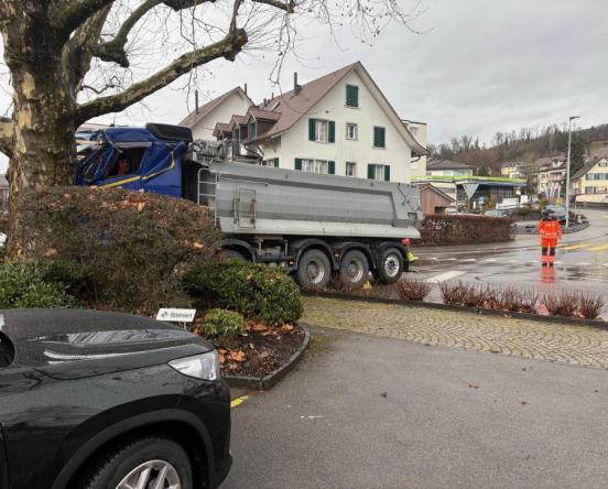 Der verunfallte Lastwagen in Unfallendstellung am Baum stehend. Im Hintergrund ein Feuerwehrmann der den Verkehr regelt.