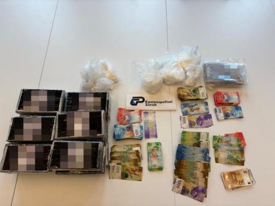 Schwarz verpacktes Kokain sowie Bargeldbündel auf einem Tisch mit dem Logo der Kantonspolizei Zürich