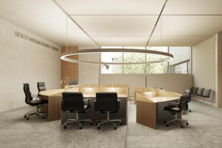 Moderner Gerichtssaal mit Holzmöbeln und schwarzen Bürostühlen. An der Wand steht «GESETZ ANGEMESSENHEIT FRIEDEN».