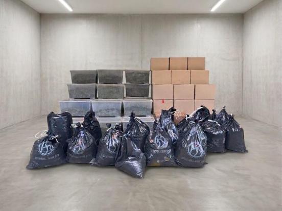 Kisten und Abfallsäcke aufgeschichtet in einem kargen Betonraum