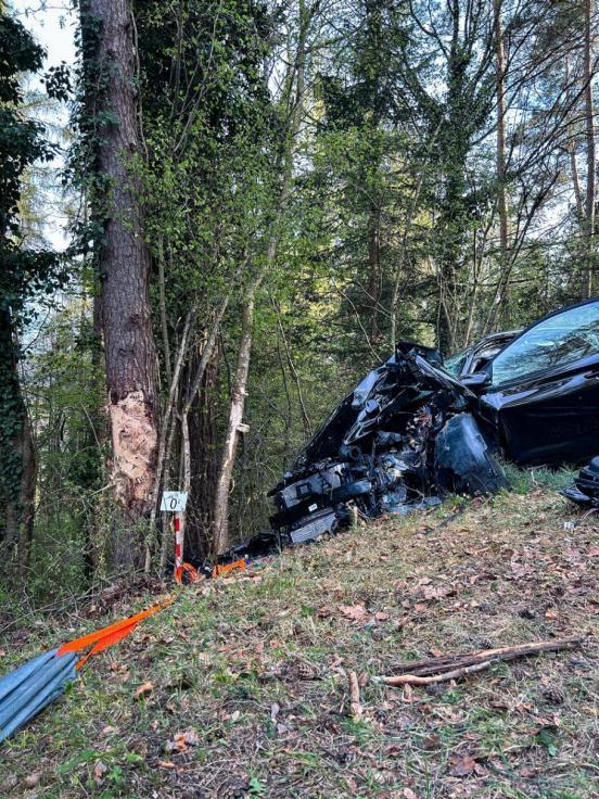 Ein schwer beschädigter Pkw liegt verlassen in einem Waldstück.