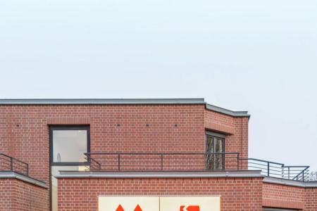 Leuchttafel mit Transportpiktogrammen (Oben, Glasbruch, Vorsicht, Zerbrechlich) an einer Ziegelsteinfassade.