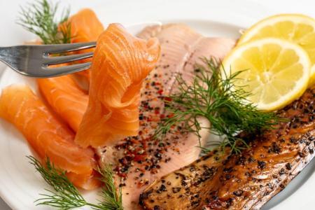 Verschiedene Fischproben, darunter roher und gegarter Fisch, mit Gewürzen und Zitrone angerichtet.