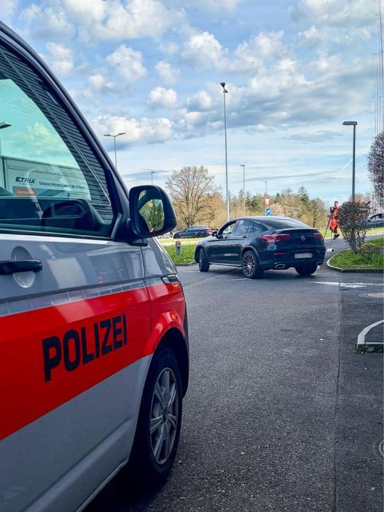 Ein Polizeiauto und ein anderes Auto stehen auf einer Strasse