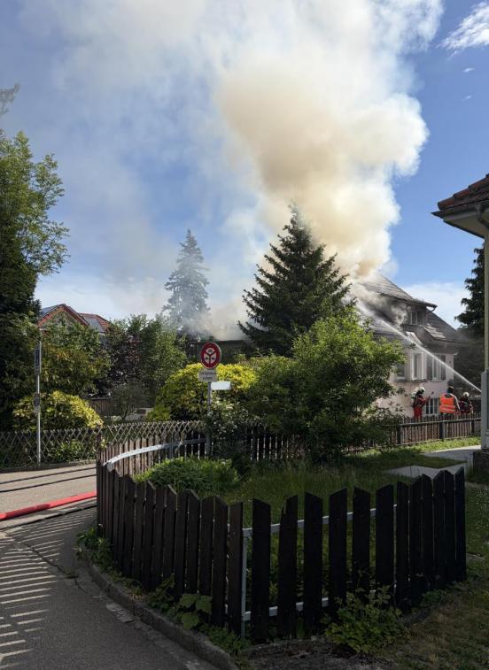 Rauchsäule steigt in den Himmel während die Feuerwehr den Brand bekämpft 