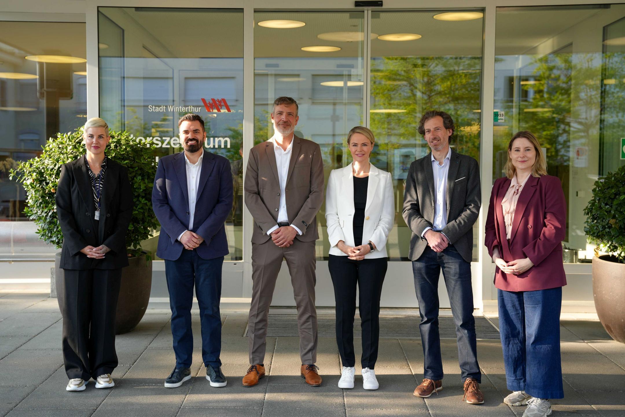 Sechs Personen stehen vor dem Eingang des Alterszentrums Adlergarten der Stadt Winterthur und posieren für ein Gruppenfoto.