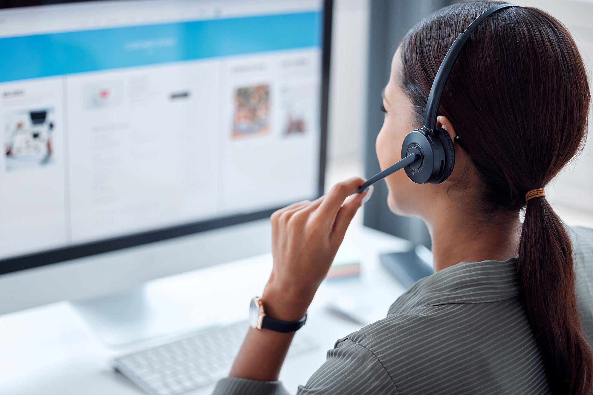 Frau mit Headset arbeitet an einem Computerarbeitsplatz.