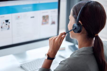 Frau mit Headset arbeitet an einem Computerarbeitsplatz.