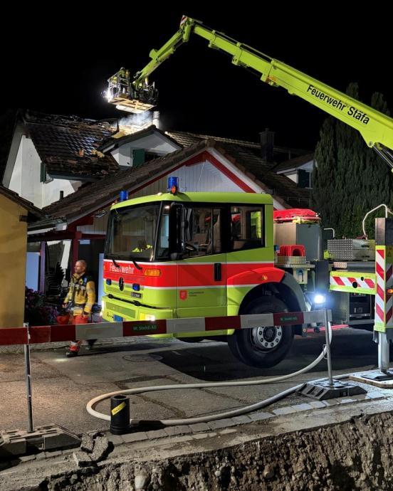 Feuerwehrhubretter vor einem Haus mit rauchendem Dachstock