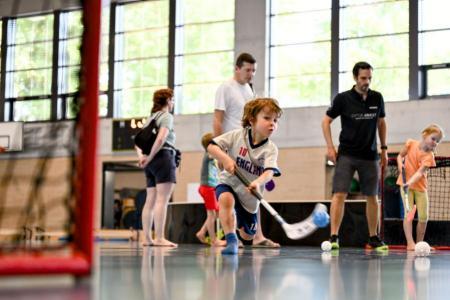 Ein Knabe spielt Unihockey in einer Turnhalle.