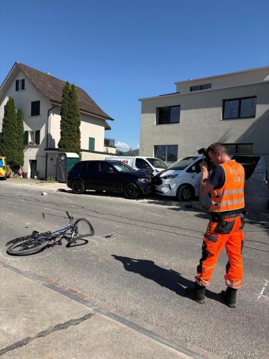 Win Polizist fotografiert das unfallbeteiligte Velo. Im Hintergrund die drei ebenfalls beteiligten Autos. Autos