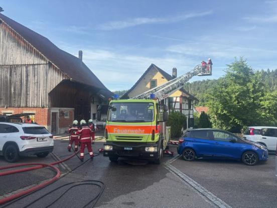 Feuerwehrdrehleiter und Feuerwehrleute stehen vor einem Haus.
