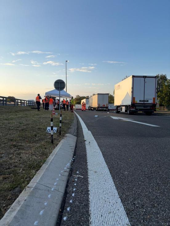 Unfallendlage. Im Hintergrund sind der Anhänger und der Lastwagen zu sehen. Links stehen mehere Einsatzkräfte.