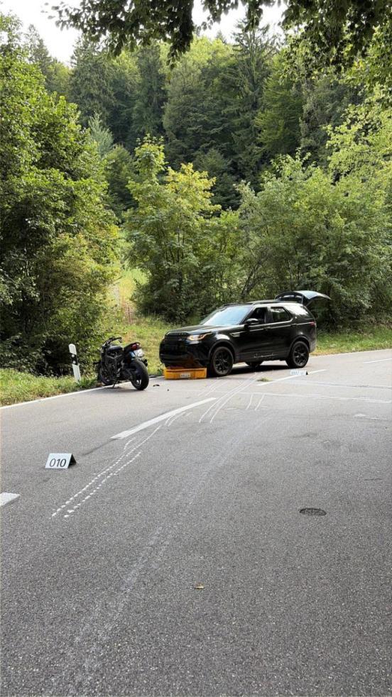 Ein SUV steht am Strassenrand, davor das Motorrad. Am Boden sich Schleiffspuren eingezeichnet.